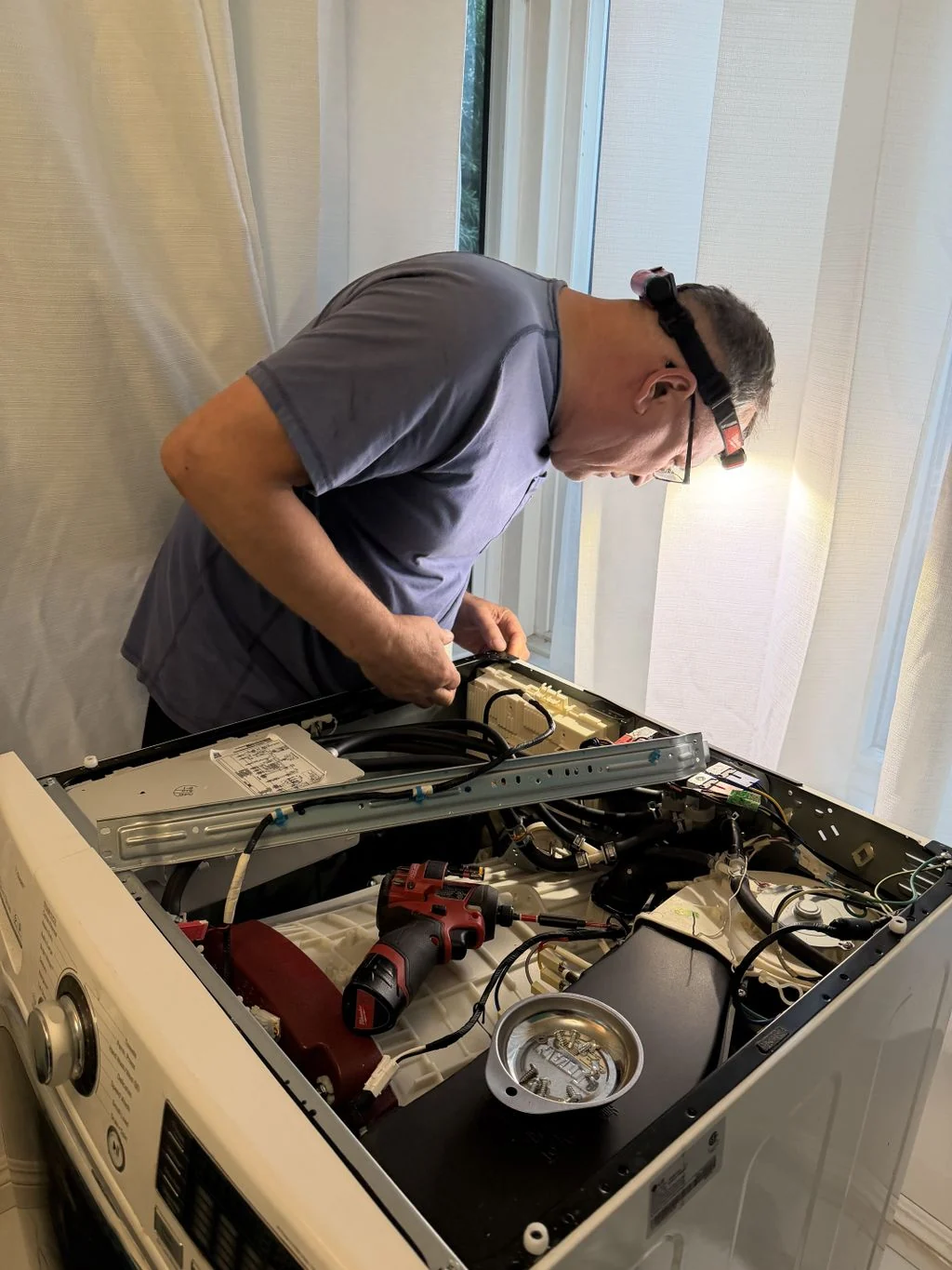 Extory technician inspecting a washing machine with its top removed